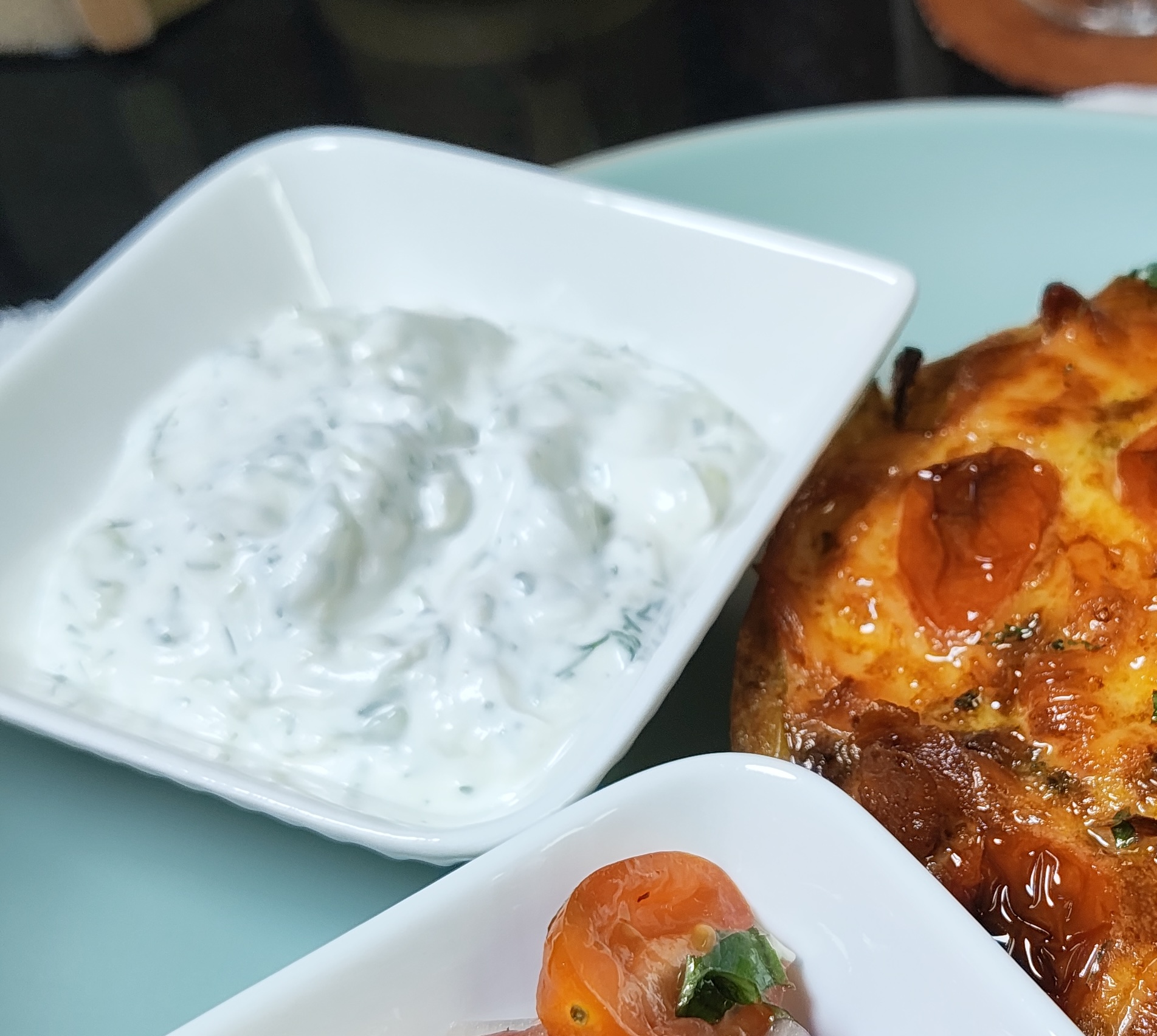 Garlic cucumber yoghurt dip with dill in a white square bowl, served beside an air fryer breakfast bake