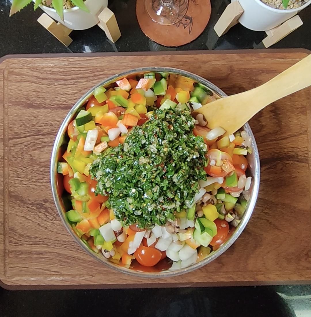 Black eyed peas and chopped vegetables with parsley and garlic dressing added before mixing