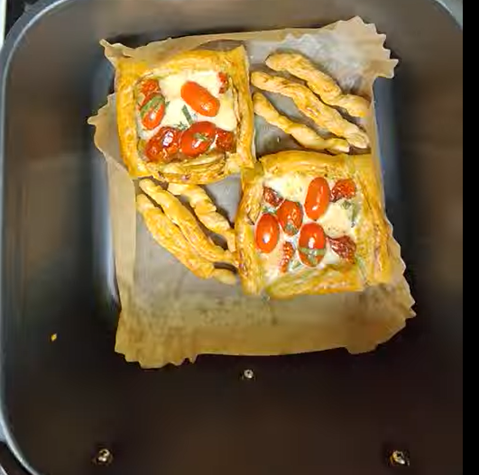 Pesto and tomato puff pastries cooking in the air fryer