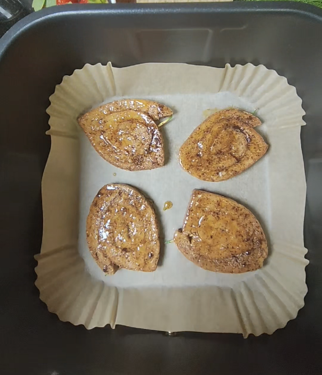 Four rolled French toast pieces in an air fryer basket