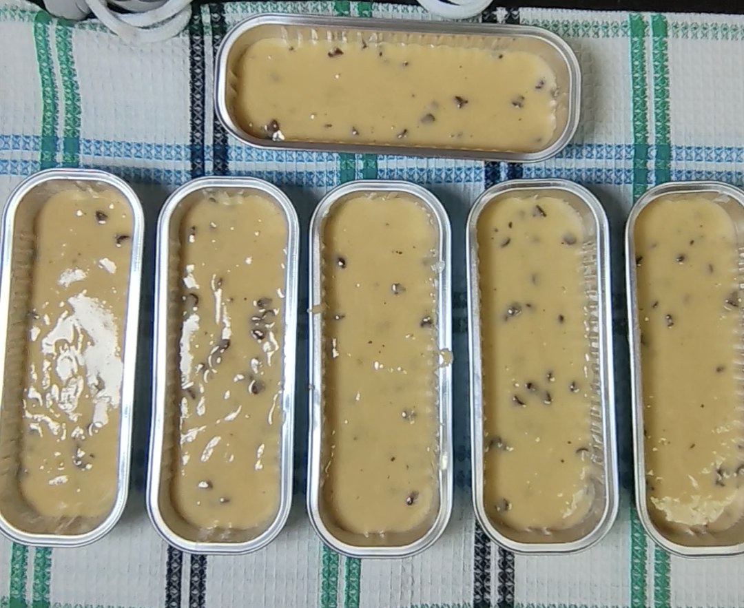 Six aluminium mini loaf tins filled with chocolate chip batter