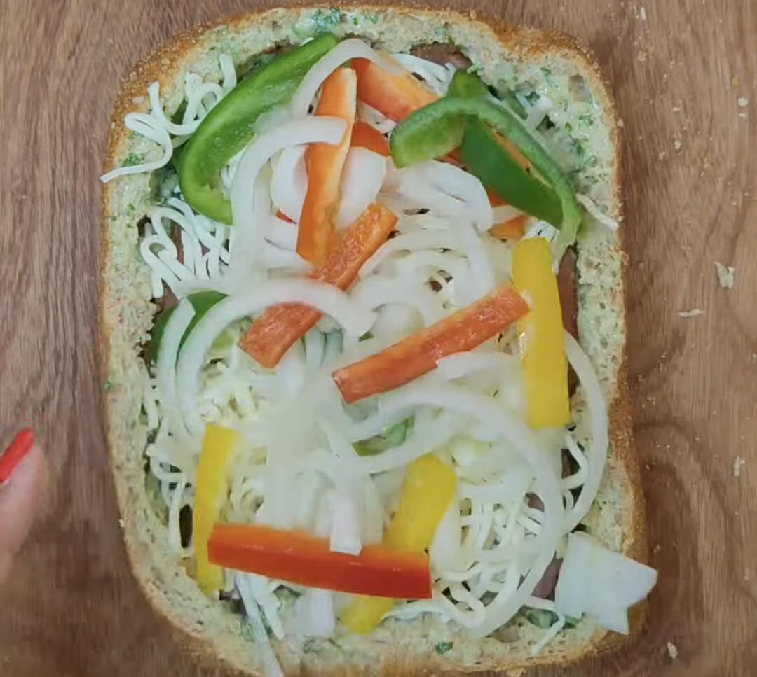 Hollowed country bread filled with grated mozzarella, colourful peppers and sliced onion