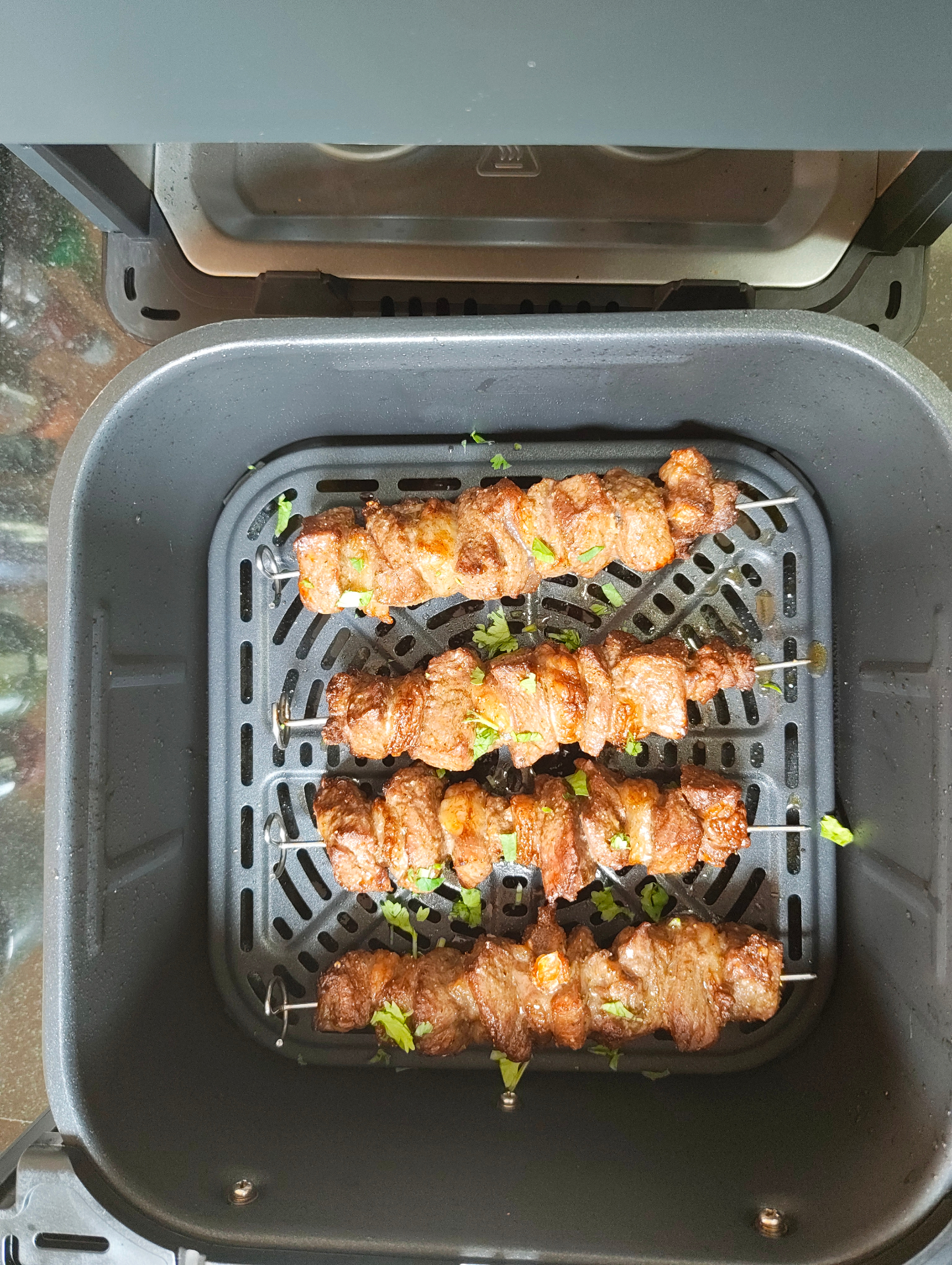 Four cooked ribeye beef skewers in an air fryer basket