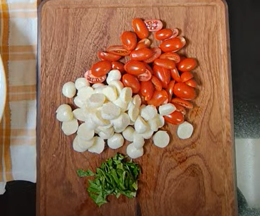 Cherry tomatoes, fresh mozzarella and chopped basil prepared for Caprese style salad