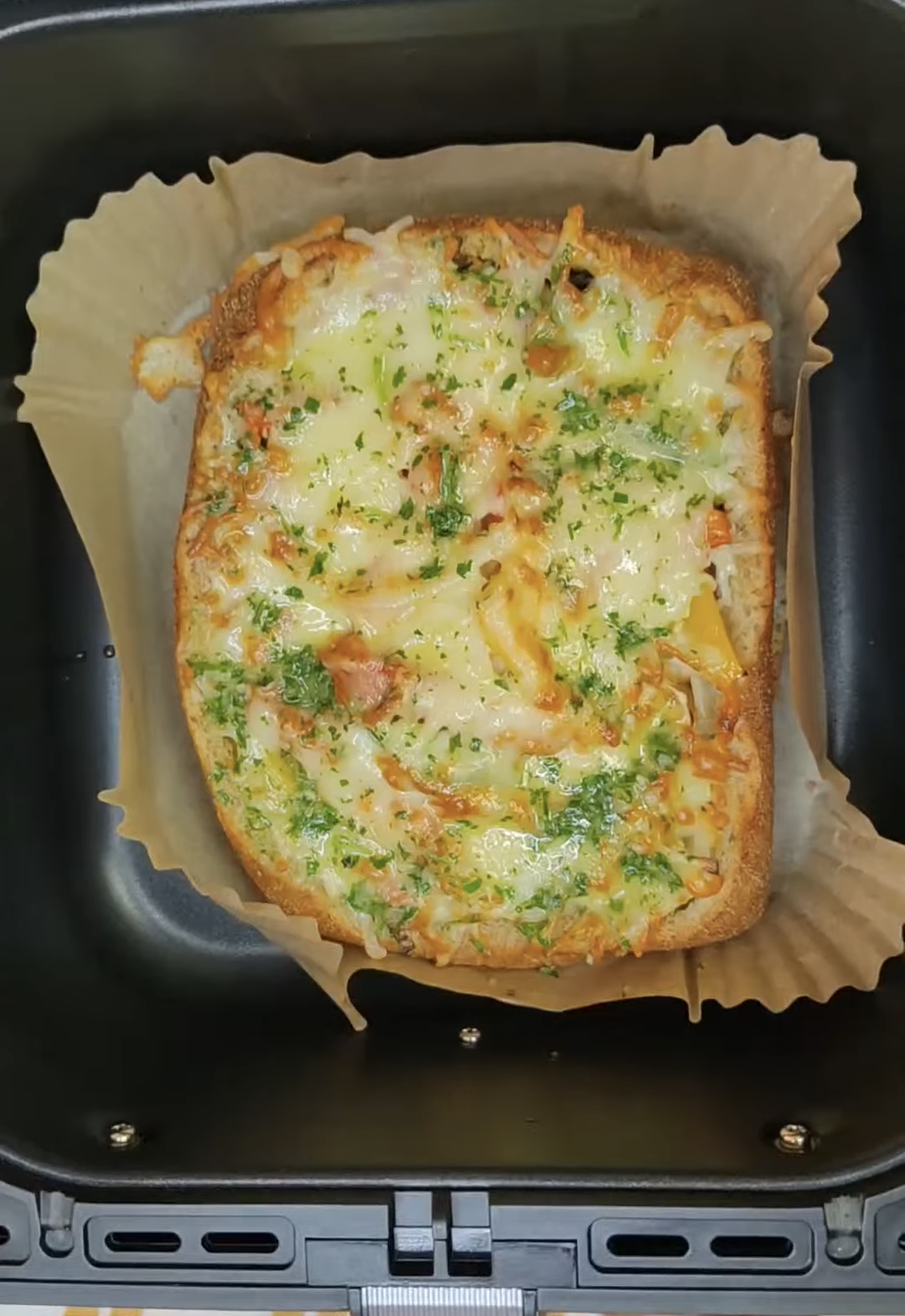 Cooked country bread with golden melted mozzarella in the air fryer basket