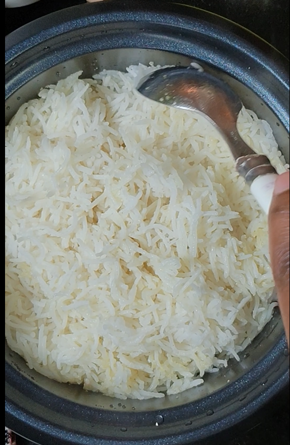 Fluffy basmati rice cooked in a rice cooker, being fluffed with a serving spoon