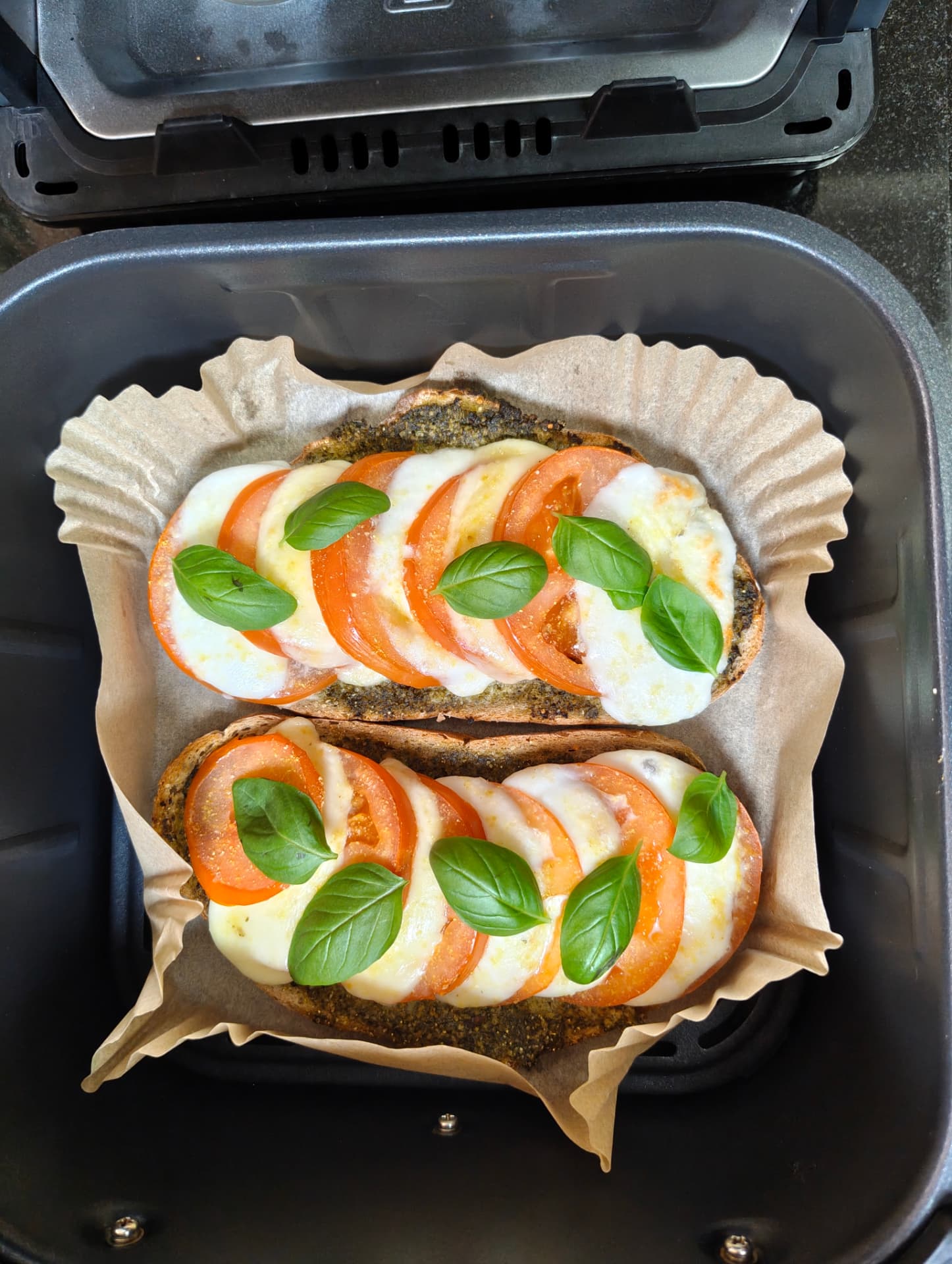 Mozzarella and tomato sourdough toast with pesto and fresh basil in the air fryer