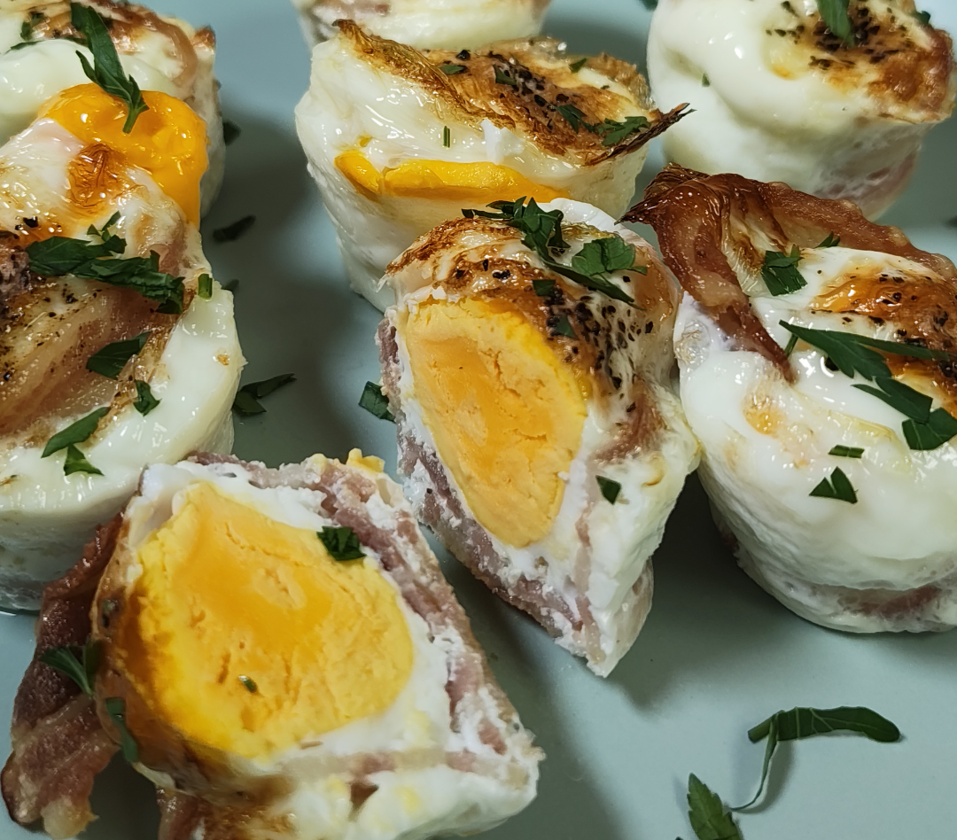 Cooked bacon and egg cups cut open to show firm yolks, garnished with parsley