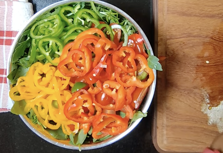 Rocket salad topped with sliced red yellow and green bell peppers