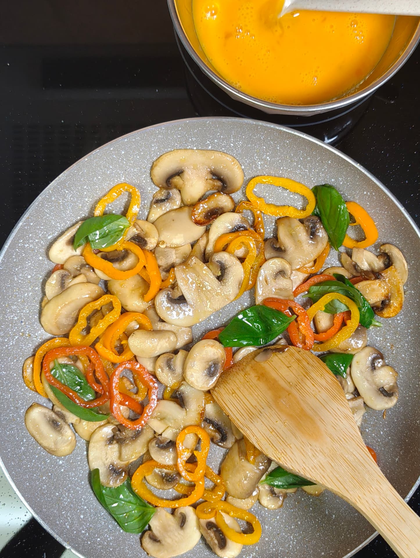 Mushrooms, peppers and fresh basil sautéing in olive oil for a cheese omelette filling