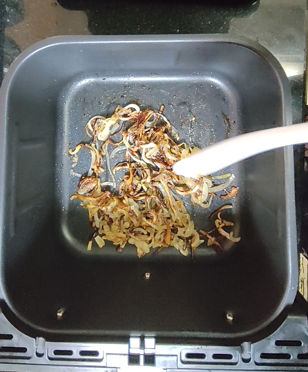 Cooked sliced onions in an air fryer basket