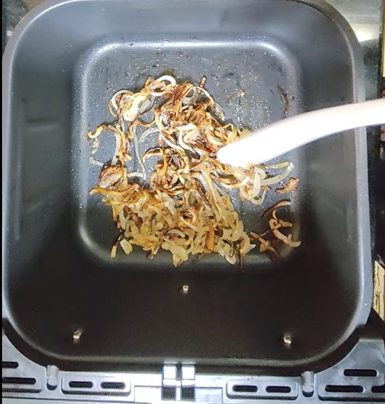 Caramelised sliced white onions inside an air fryer