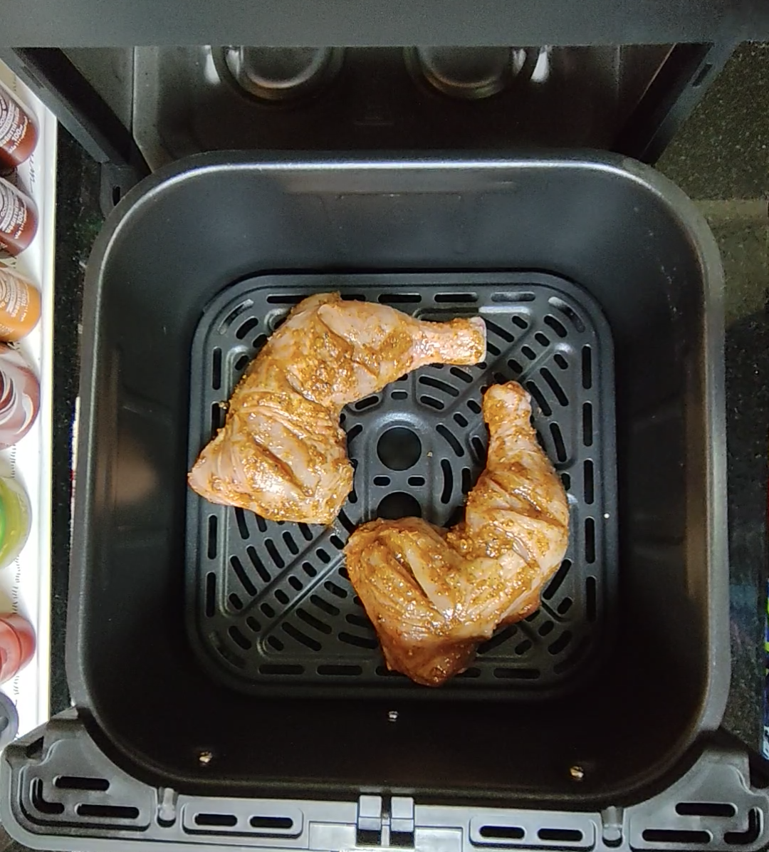 Two pieces of chicken arranged in an air fryer basket