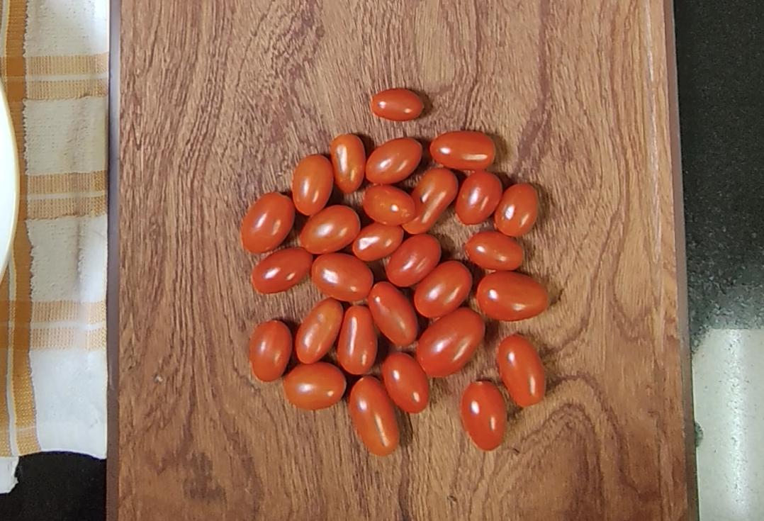 Small red tomatoes on a wooden chopping board