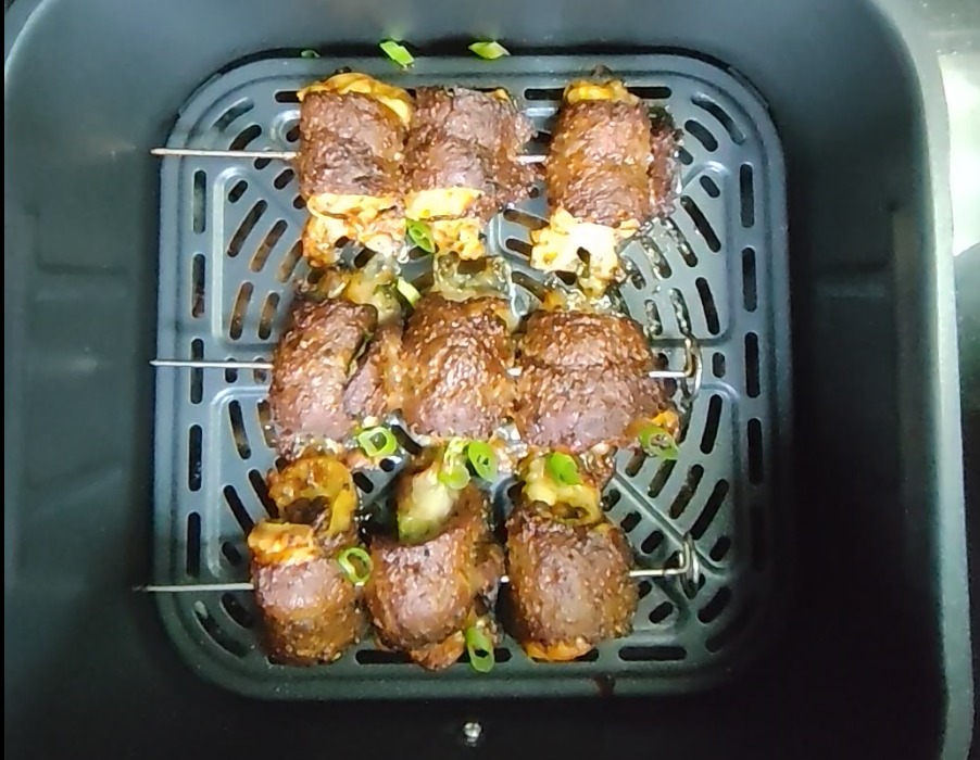 Cooked stuffed beef skewers with melted mozzarella in the air fryer basket before plating