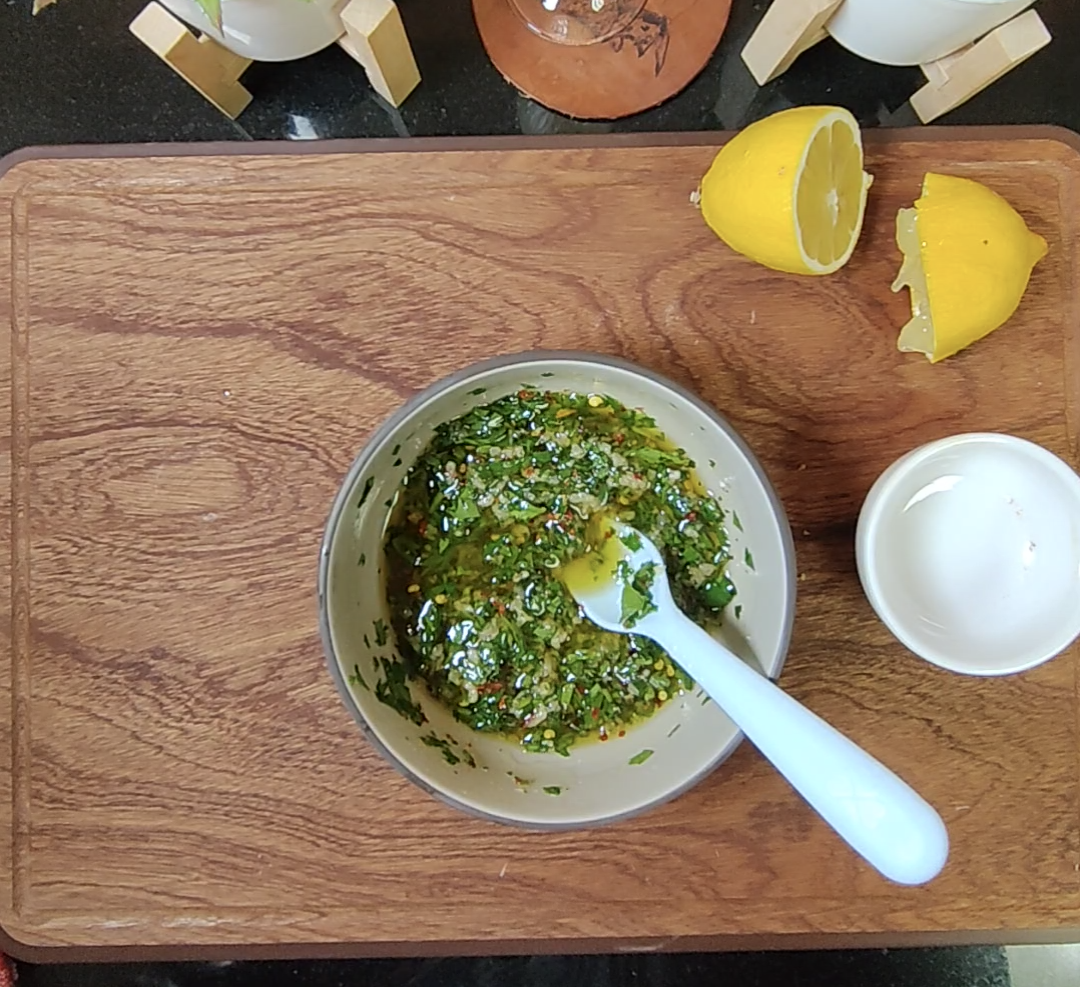 Parsley and garlic dressing in a small bowl with fresh lemon beside it