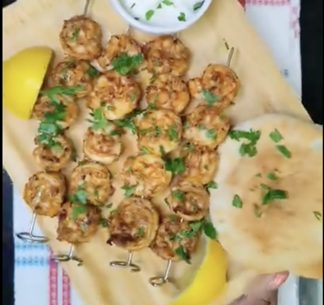 Golden air fryer shrimp skewers garnished with fresh parsley, served with flatbread and lemon