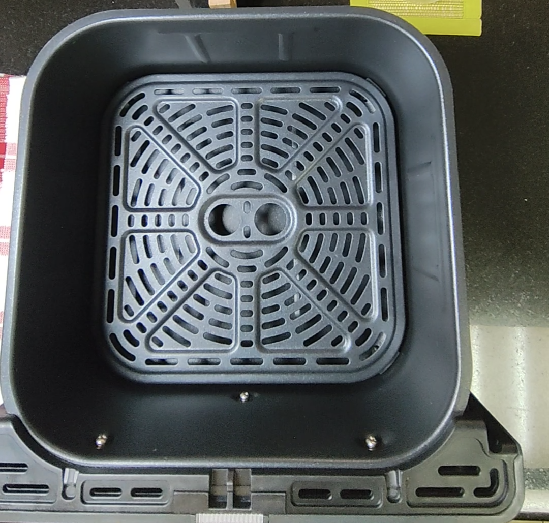 Empty air fryer basket with crisper plate showing airflow openings