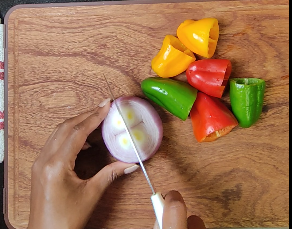 Red, yellow and green bell peppers on a wooden chopping board
