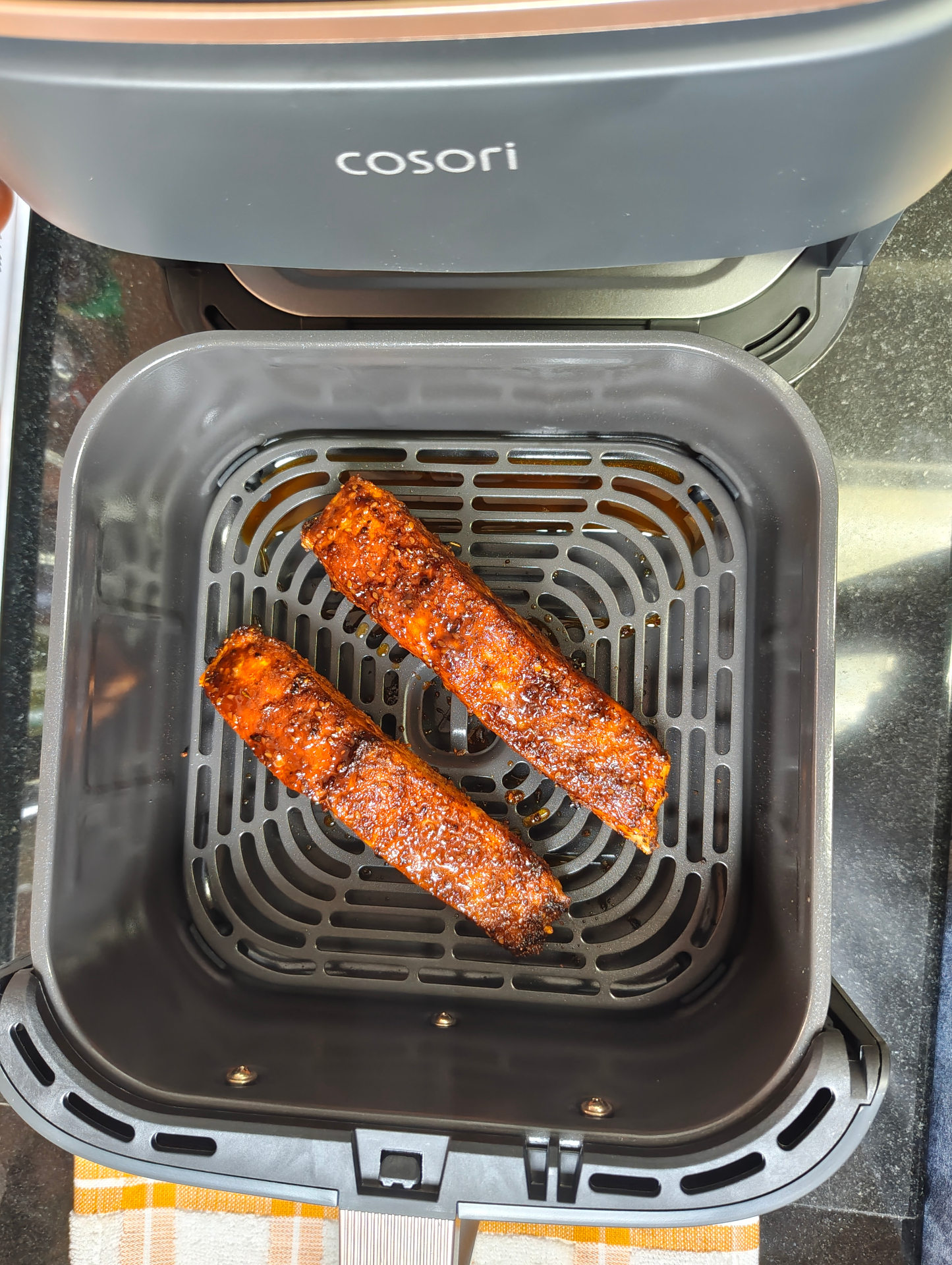 Two cooked, glazed salmon fillets in an open COSORI air fryer basket
