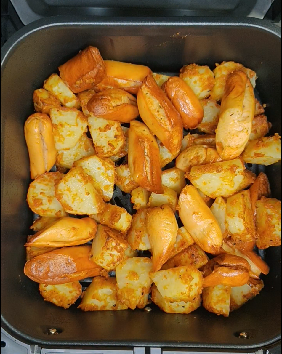Browned potato pieces in an air fryer basket