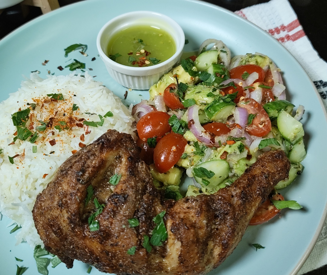 How I served it: avocado, tomato and cucumber salad on a pale blue plate with basmati rice, an air fryer chicken leg and a small ramekin of green chilli sauce