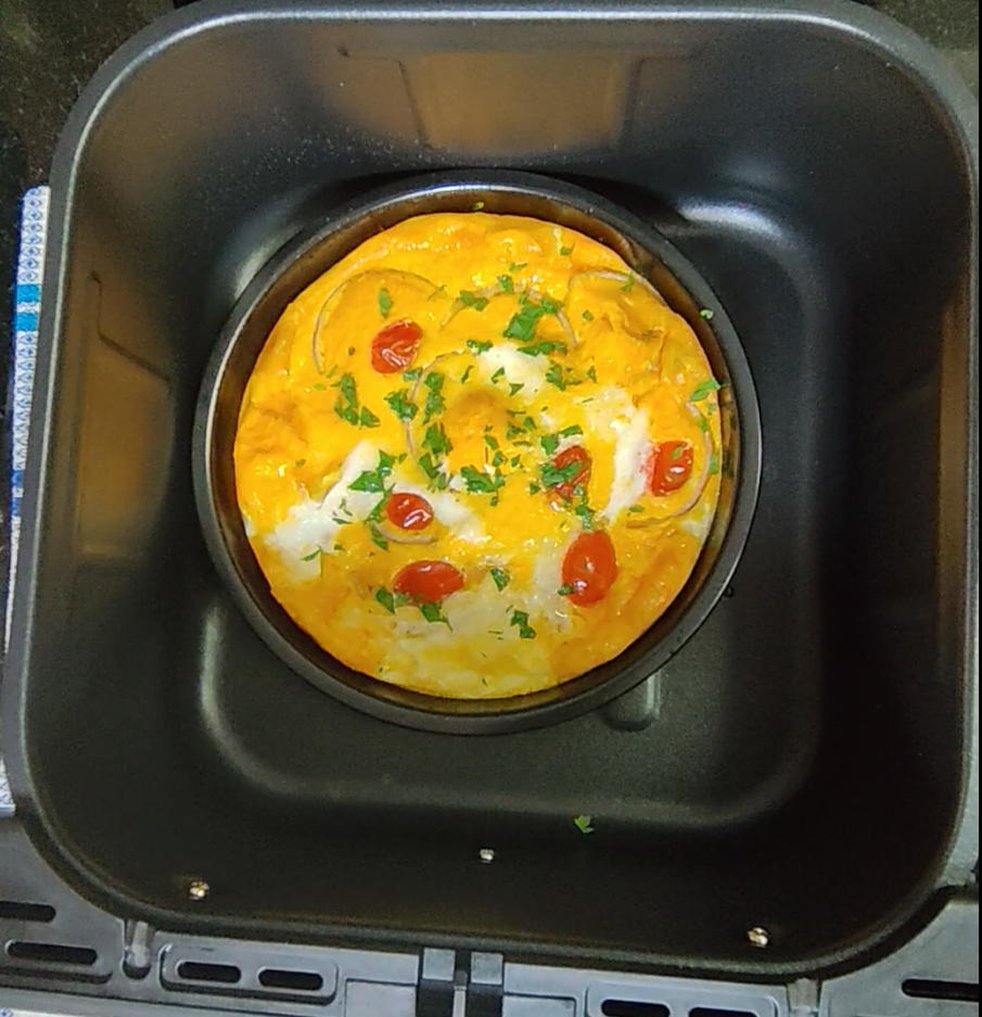 Tomato and onion omelette cooked in a round dish inside an air fryer