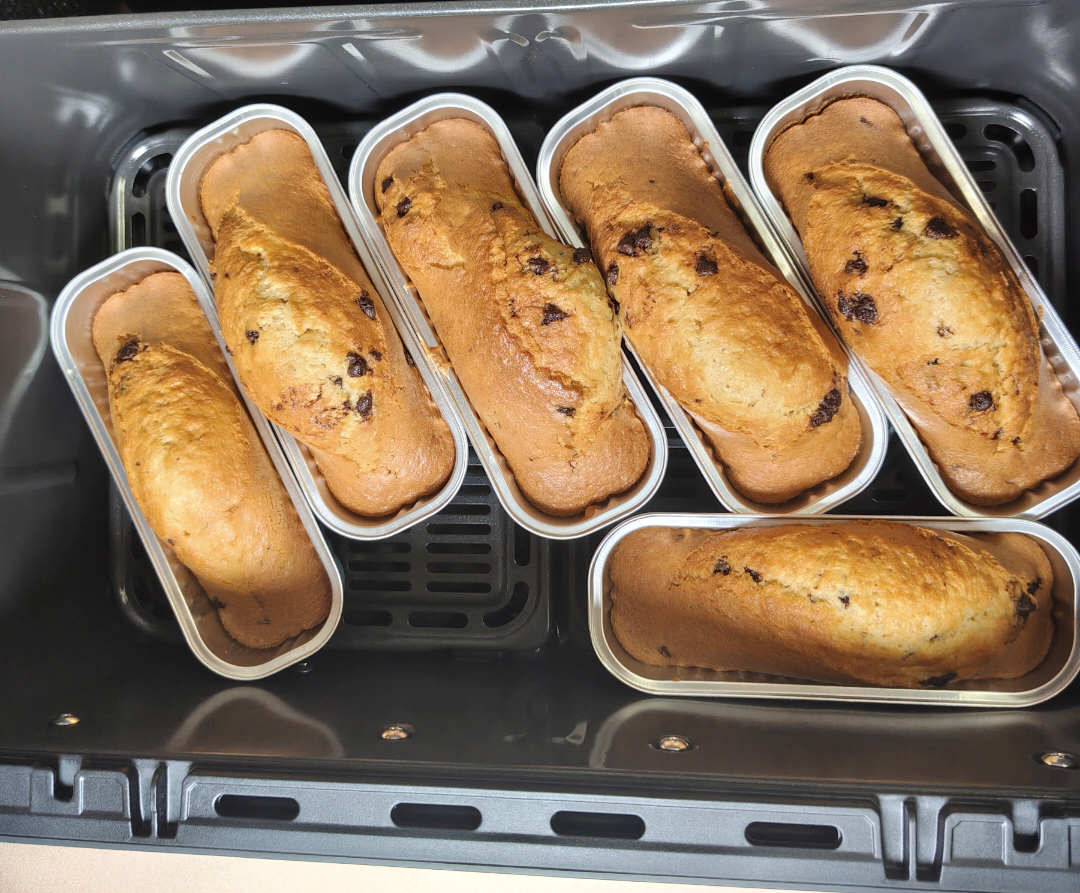 Six golden chocolate chip mini cakes baked in aluminium loaf tins inside a COSORI TwinFry air fryer