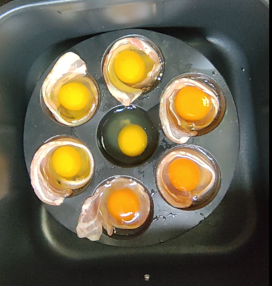 Raw bacon and eggs in a silicone mould inside an air fryer basket