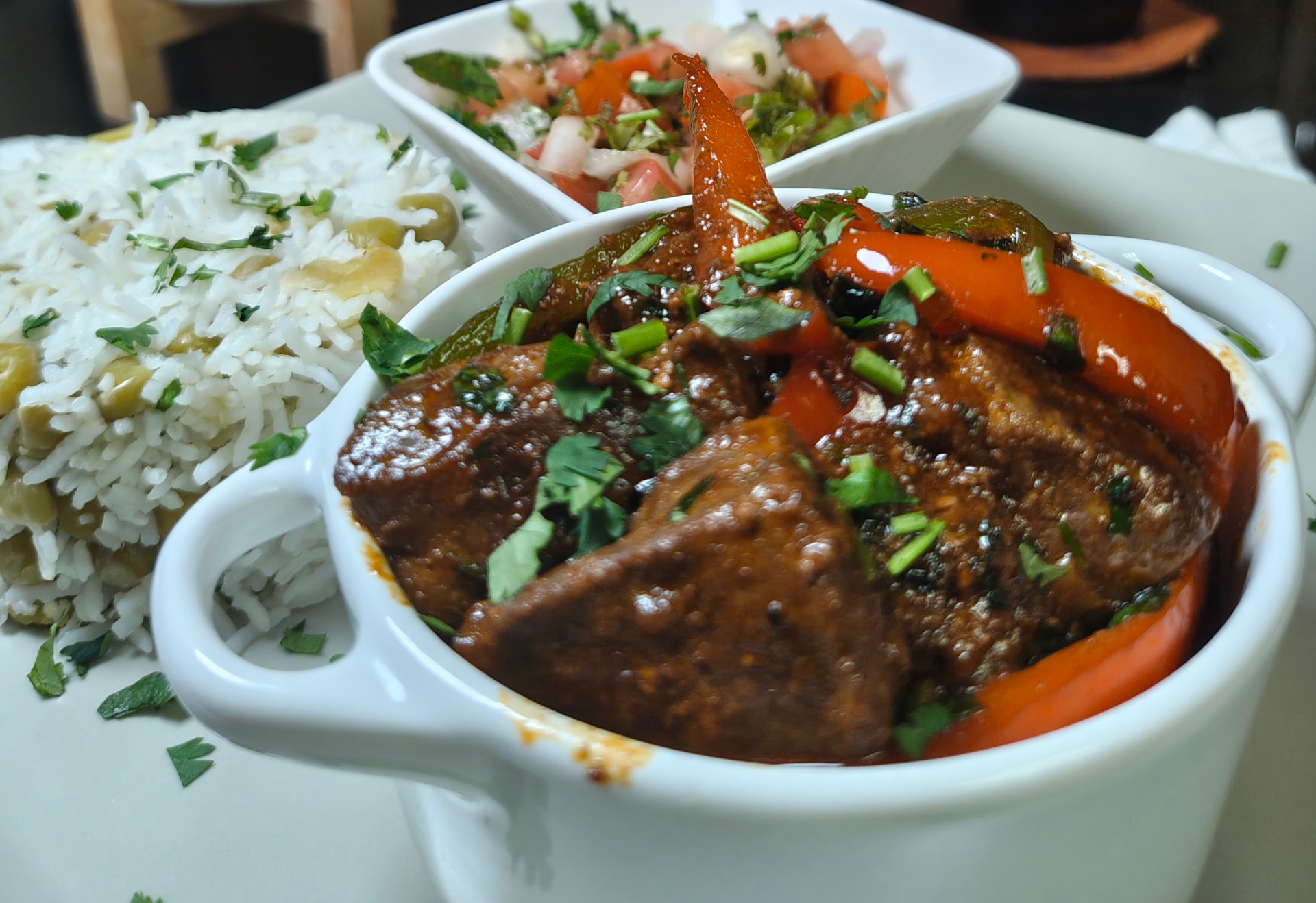 Traditional beef liver stew with red and green peppers served with basmati rice and fresh salsa