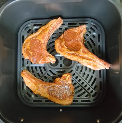 Seasoned lamb chops in a single layer in an air fryer basket