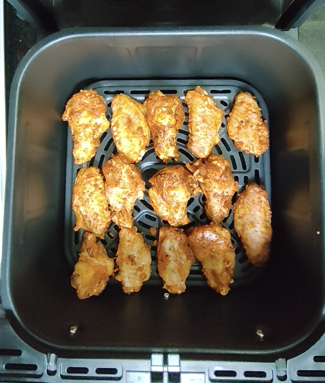 Cooked chicken wings arranged in an air fryer basket