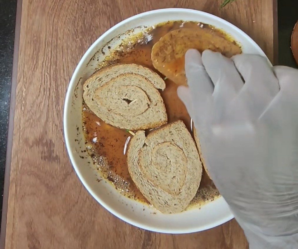 Rolled bread being coated in egg and cinnamon mixture