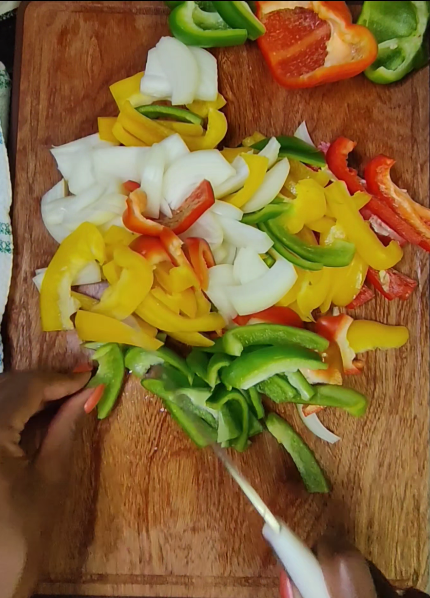Sliced red, yellow and green bell peppers on a wooden chopping board