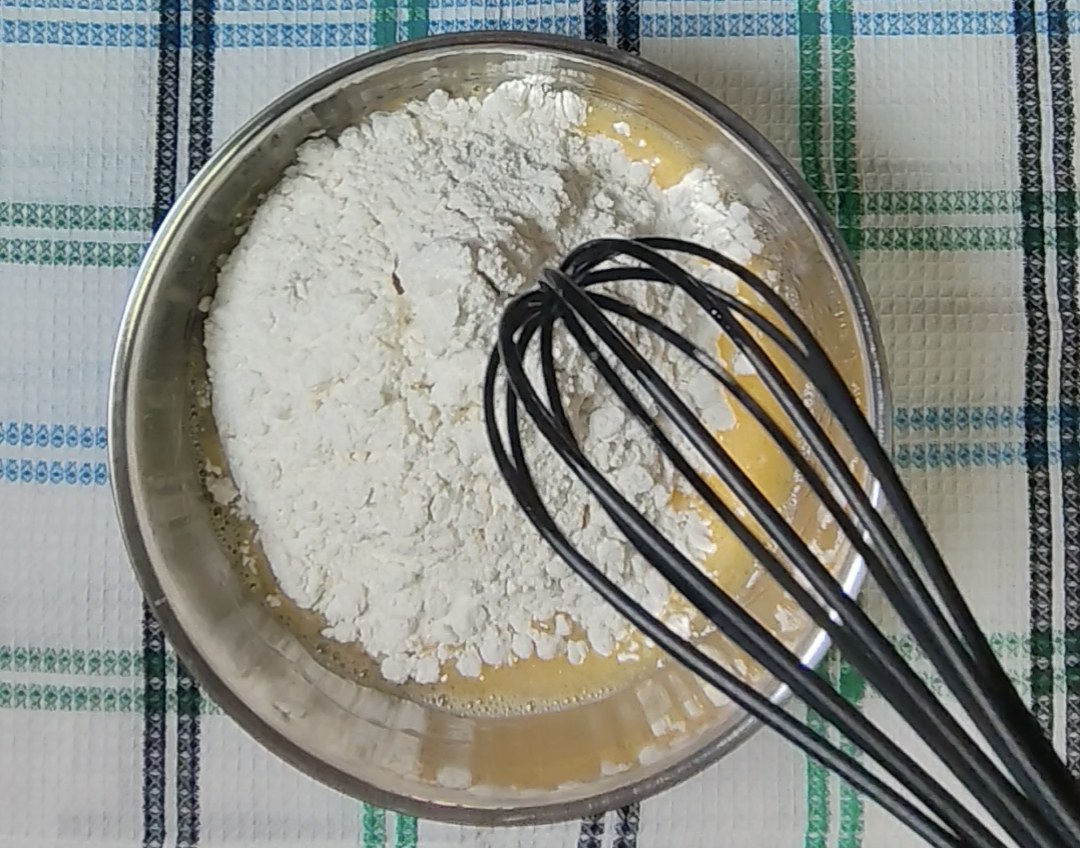 Chocolate chip muffin mix added to the wet ingredients in a mixing bowl with a whisk