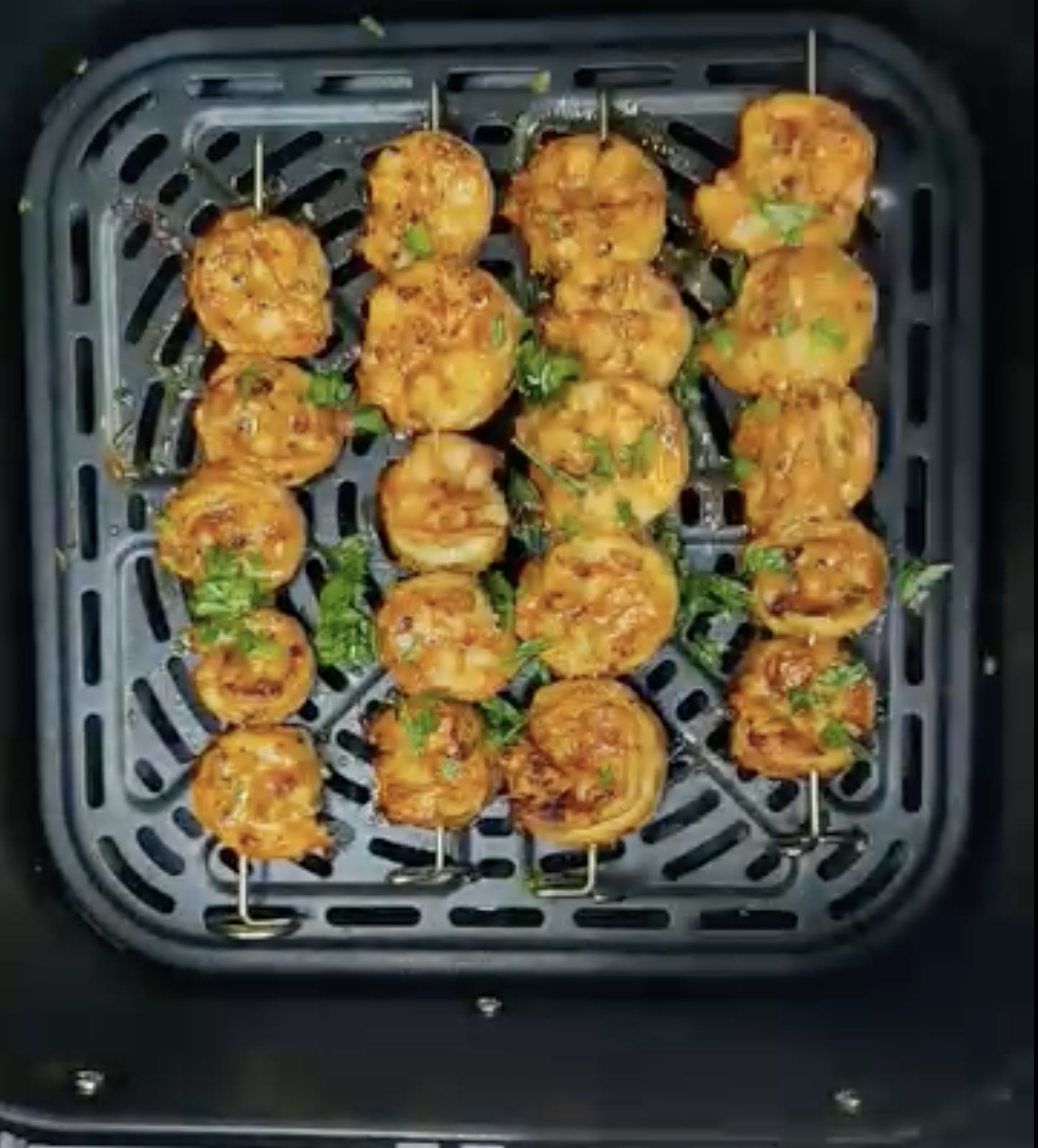 Cooked paprika shrimp skewers in an air fryer basket