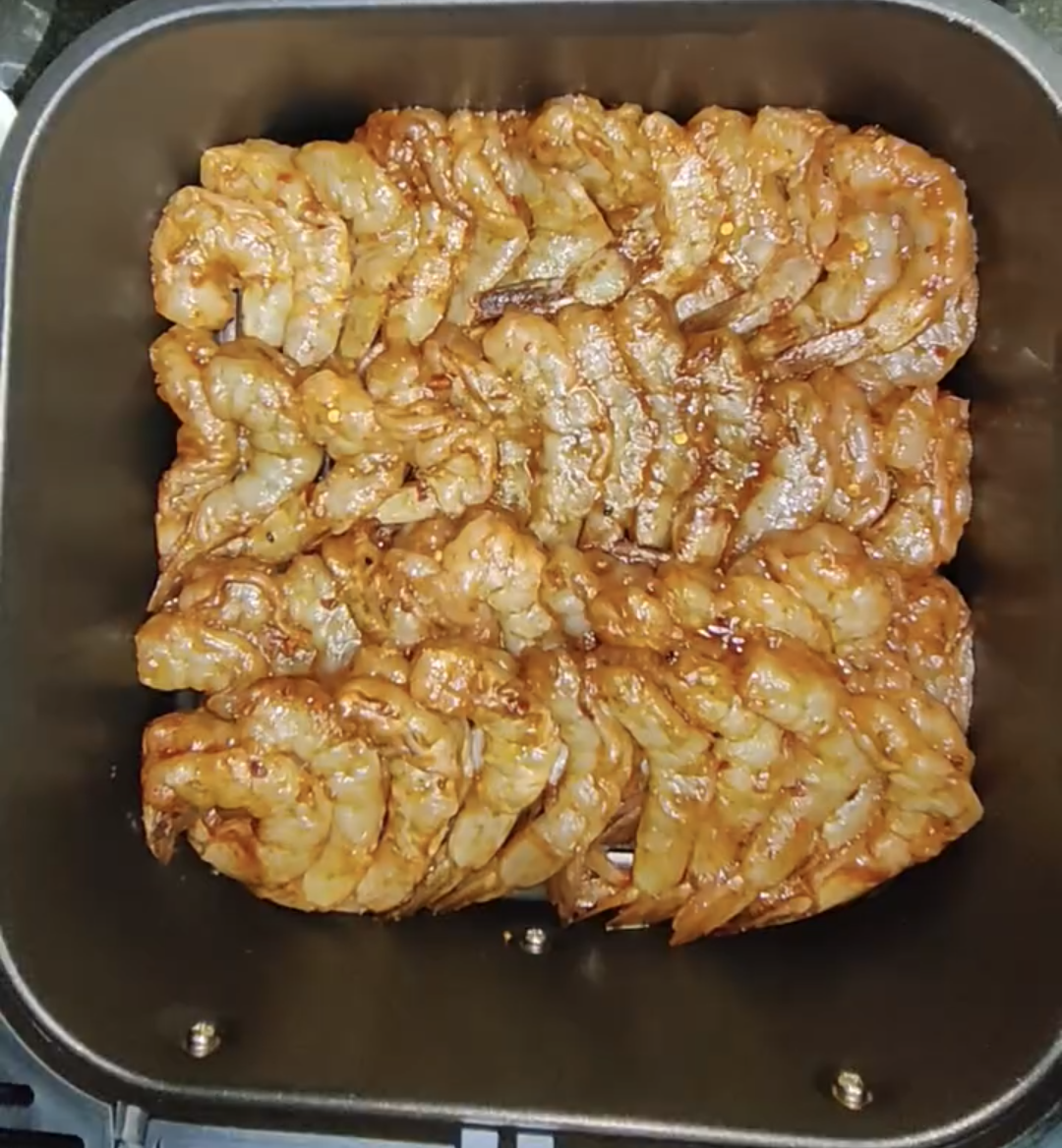 Seasoned raw shrimp arranged in the COSORI Dual Blaze air fryer basket before cooking