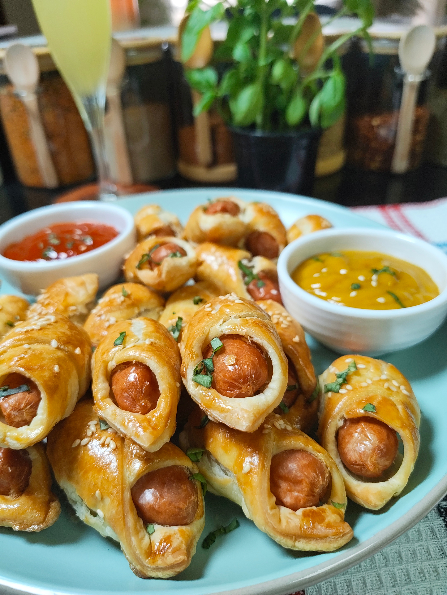 Golden air fryer mini sausage pastries piled on a blue serving plate with two dipping sauces