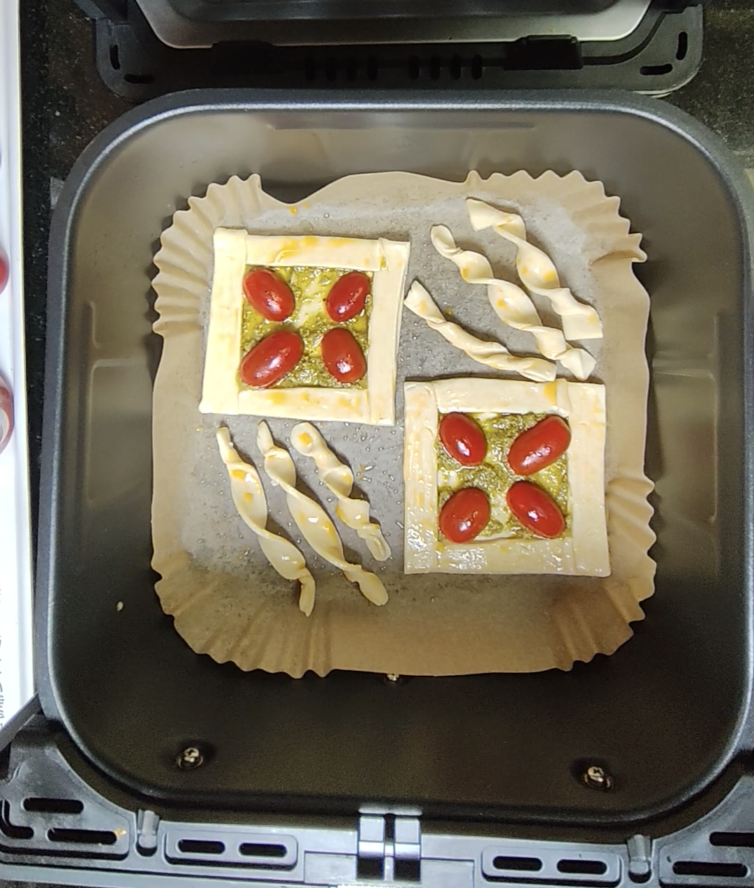 Pastry pieces arranged on a parchment-style liner in an air fryer basket