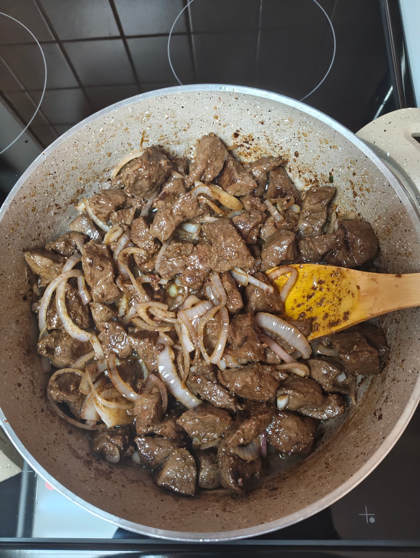Beef liver cooking with sliced onions in a pan