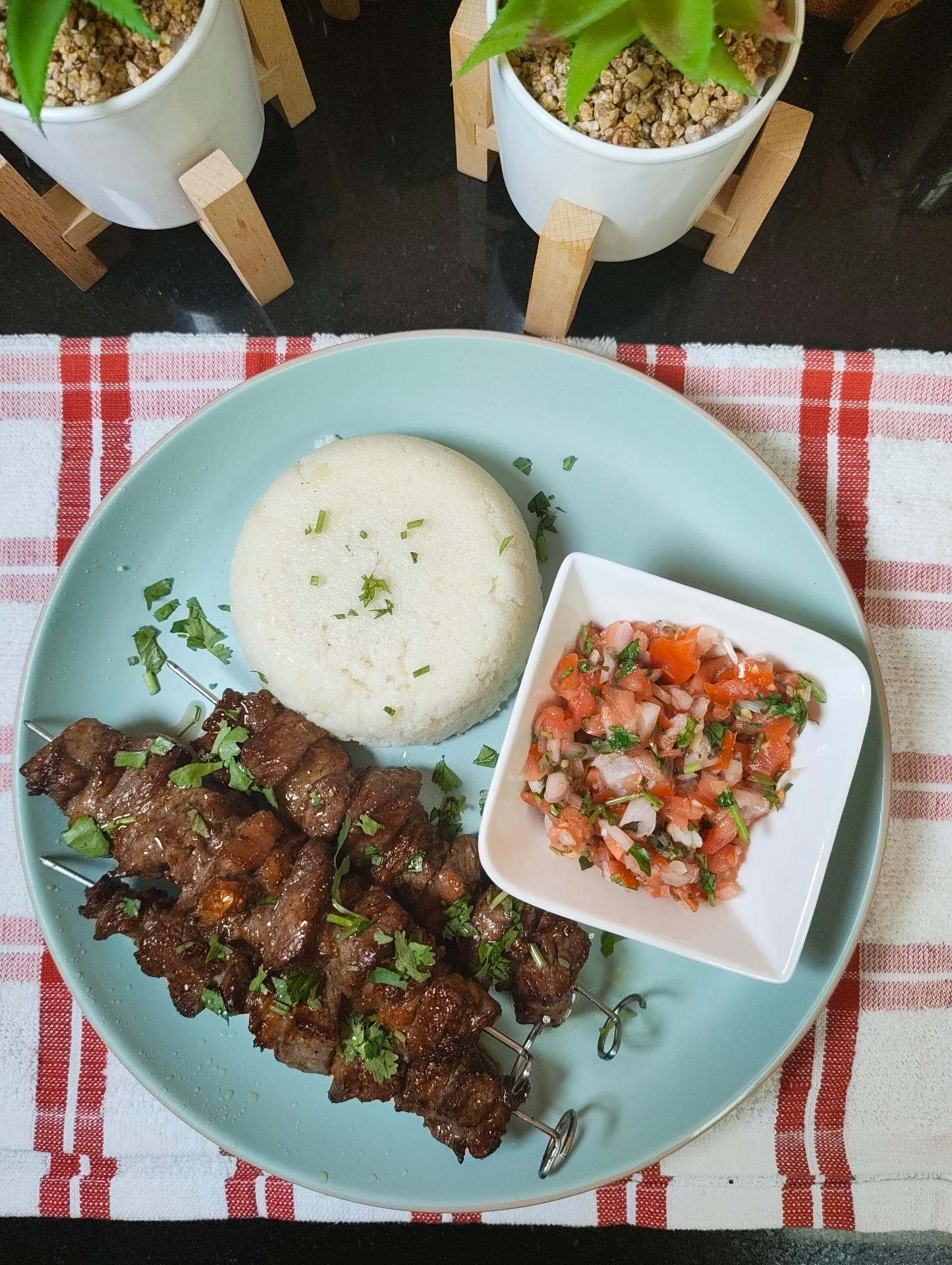 Four air fryer beef skewers served with ugali and kachumbari on a blue plate